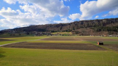 Ahşap kulübesi, ormanı ve bulutlu gökyüzünün altında dağları olan büyük bir tarla.