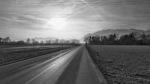 黒と白の太陽の下で道路上の背景と電源ケーブルの山と冬の風景の高速道路 — ストック写真