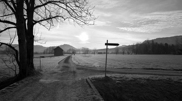 木の小屋や山を背景に黒と白の木の横の田舎道の標識 — ストック写真