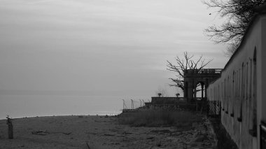 Langenargen 'deki Constance Gölü' nde günbatımında, arka planda siyah-beyaz çıplak ağaçla birlikte eski duvar boyunca uzanır.