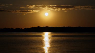 Göl kenarındaki suda yansıyan günbatımı