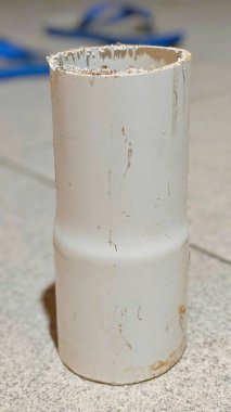 Yerde beyaz plastik boru, fotoğrafa yakın çekim. Yakın plan..
