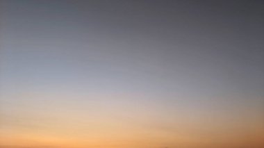 Mavi, mor ve turuncu tonlarıyla eğimli gökyüzü. Renkler kusursuz bir şekilde karışıyor ve güzel bir etki yaratıyor. Ufuk zar zor görünüyor, gökyüzüne karışıyor..