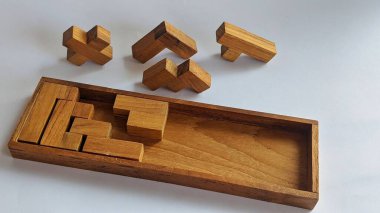 A wooden puzzle box with various wooden pieces inside. The box has a rectangular shape and is made of dark wood. The pieces are of different sizes and shapes, and some have intricate carvings. clipart