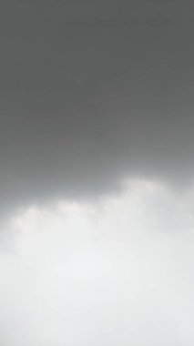 Koyu gri ve açık gri bulutların karışımı bulutlu bir gökyüzü. Bulutlar kalın ve hızlı hareket ediyor gibi görünüyor. Gökyüzünün karanlık ve aydınlık bölgelerini ayıran farklı bir çizgi vardır..