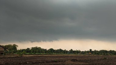 Koyu gri ve açık gri bulutların karışımı bulutlu bir gökyüzü. Bulutlar kalın ve hızlı hareket ediyor gibi görünüyor. Gökyüzünün karanlık ve aydınlık bölgelerini ayıran farklı bir çizgi vardır..
