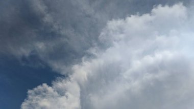 A towering cumulus cloud dominates the sky, its fluffy, white form contrasting against the deep blue backdrop. The image evokes a sense of wonder and the vastness of nature. clipart