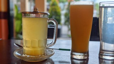 Farklı içeceklerle dolu üç bardak ahşap bir masaya dizilir..