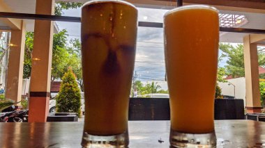 Farklı içkilerle dolu iki uzun bardak ahşap bir masaya konur..