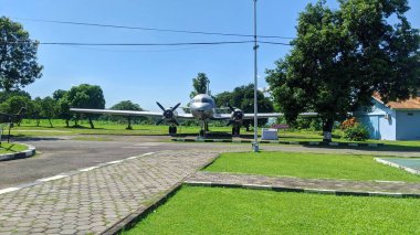 Kaliteli bir pervane uçağına sahip bir açık hava havacılık müzesi. Açık mavi gökyüzünün altında yemyeşil çimenler ve ağaçlarla çevrili asfalt bir alanda sergileniyor..