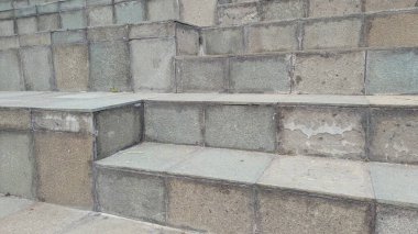 Birden fazla geniş basamaklı, soluk gri ve yeşil paletli, aşınmayı ve doğal dokuyu gösteren bir açık hava taş merdiveni..