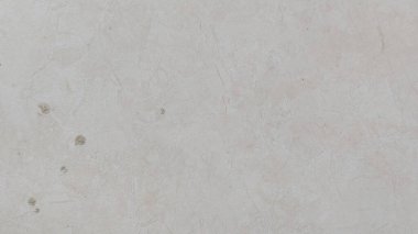 Kırsal, dokulu, ince renk değişiklikleri ve küçük kusurları olan bir duvarın yakın çekimi. Açık bej yüzey, minimalist, eski bir havası olan grunge bir arka plan görevi görür..