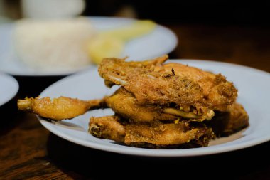 Beyaz tabakta kızarmış tavuk, dar bir alan derinliği.