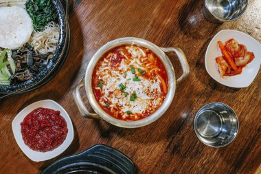 Tteokbokki olarak bilinen Kore mutfağının yüksek çözünürlüklü fotoğrafı alüminyum bir tavada diğer yiyeceklerin merkezinde.