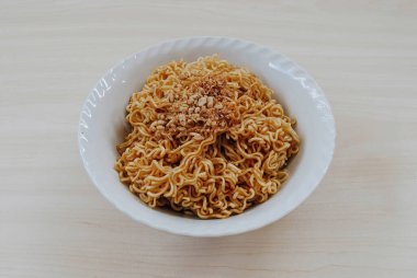 Büyük beyaz bir kasede kızarmış soğanlı hazır eriştenin yüksek çözünürlüklü fotoğrafı.