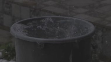 Sızdıran bir çatıdan düşen yağmur suyunu toplamak için kullanılan mavi bir kova.