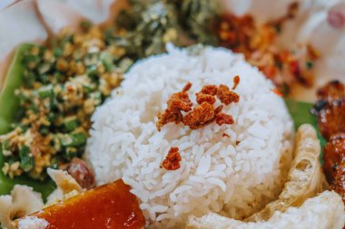 Beyaz pirincin üzerinde çıtır çıtır domuz derisi ve bir tabak Nasi Babi Guling.