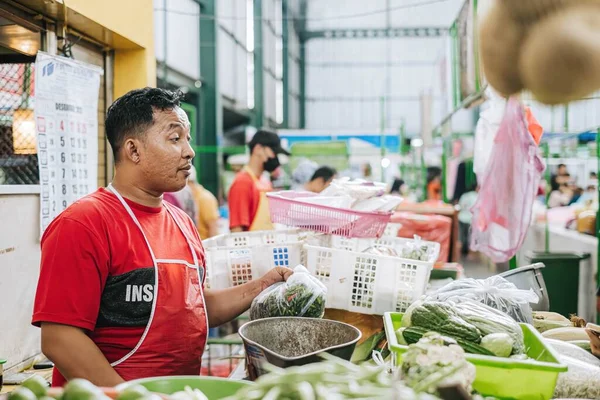 Kırmızı tişört ve önlük giyen Endonezyalı bir satıcının yüksek çözünürlüklü fotoğrafı geleneksel markette Bokeh ile birlikte