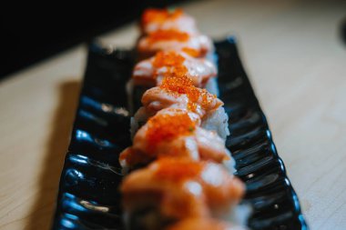 Bokeh ya da bulanık arkaplan ve önplanı olan bir grup tobiko suşisinin orta açı fotoğrafı