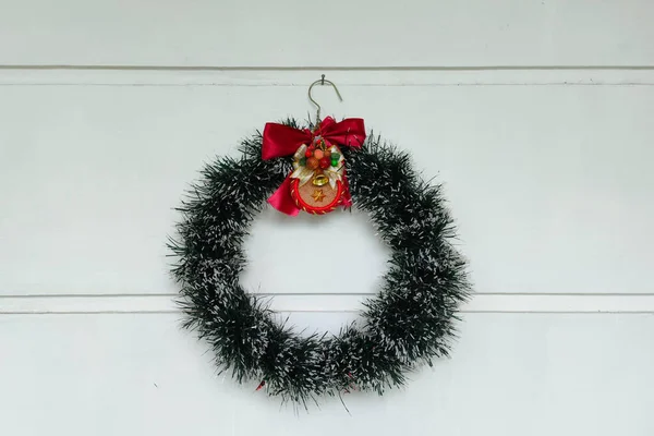 Christmas wreath decoration is hanging on the white wall as background