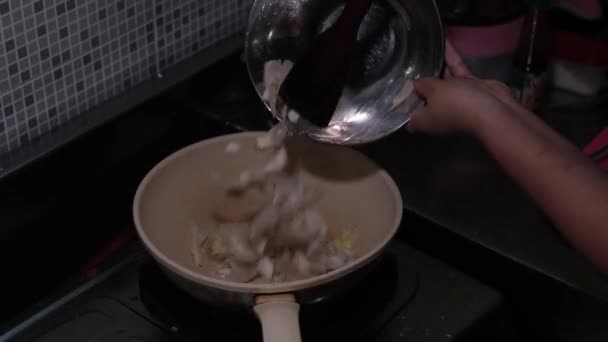 一个女人的手把生蘑菇放进油锅搅拌的录像 — 图库视频影像