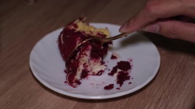 Küçük yuvarlak tabakta kırmızı kadife pastayı dilimleyen bir elin video görüntüleri.
