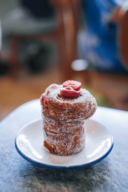 Close-up photo of a traditional easter cake called Cruffin or Kraffin on a small white plate with bokeh