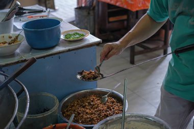 Cava dilinde Endonezya sebzeli böreği, Ote-Ote ya da Heci yapmak için spatulaya domuz eti döken bir adam. Bokeh veya bulanık arkaplan.