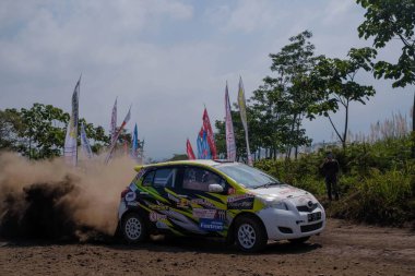 Puslatker TNI Al Bedali Lawang, Malang 'da, Kejurnas Sprint Rallisi 2023' te beyaz, siyah ve sarı bir Yaris çok toz üretir. Hareket bulanıklığı. 21 Mayıs 2023.