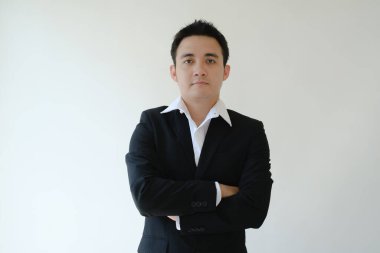 Genç Asyalı işadamı kameranın önünde dikilip resmen bakıyor. İzole edilmiş beyaz arkaplan.