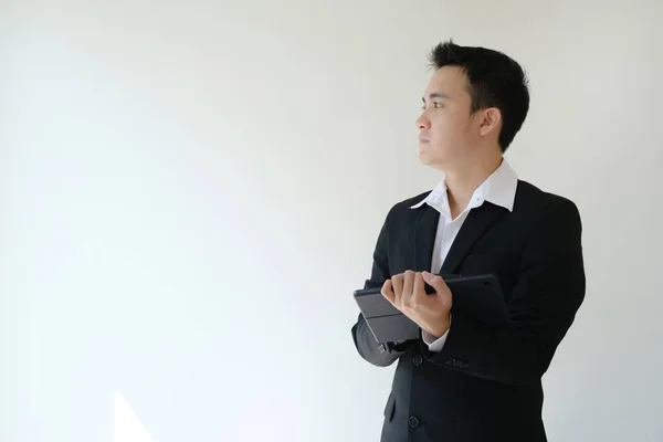 年轻的亚洲商人拿着平板电脑 看着他的右边 孤立的白色背景 — 图库照片
