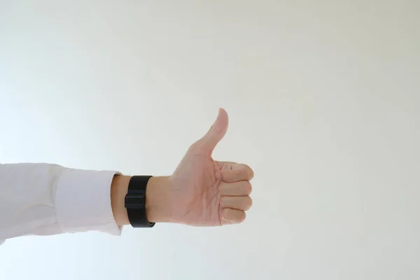 stock image A hand with a white shirt and a watch giving thumb up. Isolated white background.