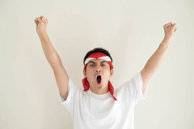 Beyaz tişört giyen genç bir Asyalı adam ve Kemerdekaan Endonezya kostümü ifadeyle heyecanlanıyor. Endonezya Bağımsızlık Günü. İzole edilmiş beyaz arkaplan.