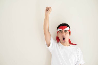 Beyaz tişört giyen genç bir Asyalı adam ve Kemerdekaan Endonezya kostümü ifadeyle heyecanlanıyor. Endonezya Bağımsızlık Günü. İzole edilmiş beyaz arkaplan.