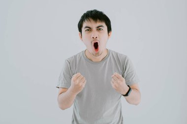 Genç Asyalı adamın seçici odak noktası, adaçayı yeşili bir tişört ve heyecanlı bir jest ve yüz ifadesi olan akıllı adam, izole edilmiş beyaz arka plandaki kameraya bakıyor.