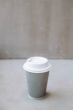 Bir endüstriyel kafede ya da izole edilmiş gri arka plandaki tek kullanımlık kağıt bardakta bir fincan kahvenin portresi ya da dikey ve seçici odak noktası