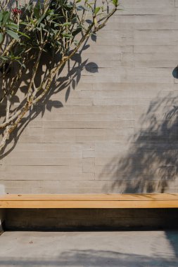 Soyut duvara monte edilmiş ahşap bir bank betondan yapılmıştır ve bir ağacı vardır.