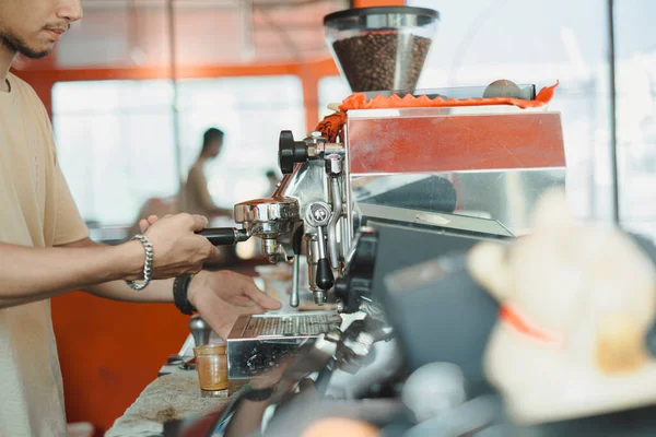An Asian man is brewing a coffee using automatic espresso maker machine