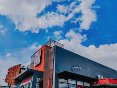 Kentucky Fried Chicken olarak bilinen KFC açık mavi gökyüzüne karşı. Amerikan fast food zinciri restoran şirketi. Malang, 17 Ağustos 2023.