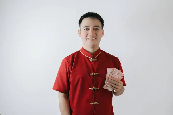 Smile face of Asian man wearing Cheongsam or Chinese traditional cloth while holding amounts of money and looking at the camera on white background