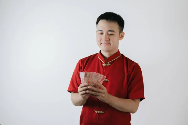 Smile face of Asian man wearing Cheongsam or Chinese traditional cloth holding amounts of money on white background