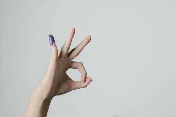A hand with OK gesture and purple ink applied on little finger after pemilu or Indonesian presidential election