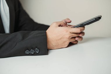 Profesyonel bir adamın eli akıllı bir telefonda daktilo çalıyor. Seçici odak.