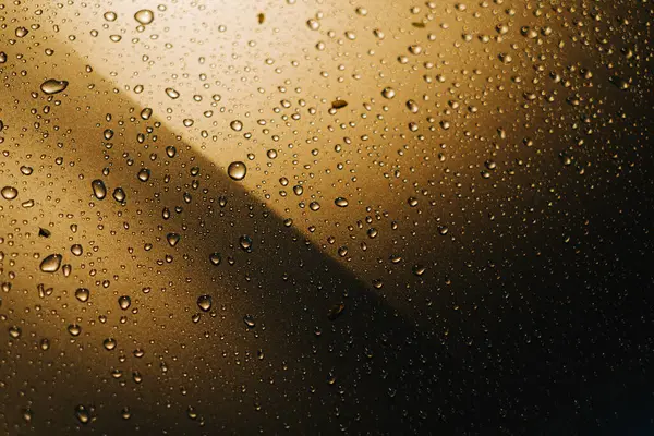 Bokeh önplanı ve arkaplanı olan arabada yağmur damlaları