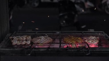 Metal örgü tokasıyla taze balık pişiriyor ve gece yanan kömürle ızgara yapıyor.