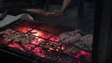 Metal örgü tokasıyla taze balık pişiriyor ve gece yanan kömürle ızgara yapıyor.
