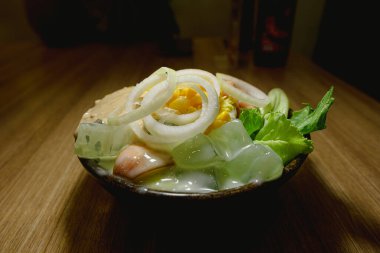 Sebzeli salata ve mayonez, ahşap masada siyah bir kâsede.