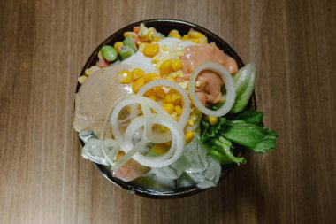 Sebzeli salata ve mayonez. Tahta masadaki siyah kasede. Düz yatış, üstten veya üstten görünüm açısı.