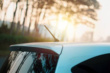 Üzerinde anten radyosu olan gümüş renkli bir araba. Gün batımında gün batımına karşı.