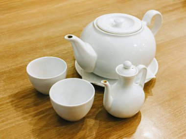 Ahşap bir masada beyaz porselen çaydanlık.